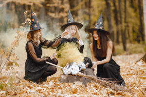 Three witches in forest on Halloween make magic potion