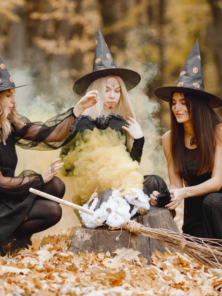 Three witches in forest on Halloween make magic potion